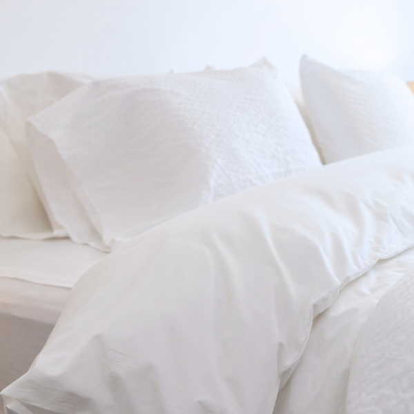 A BED MADE UP IN WHITE SHEETS AND BEDDING