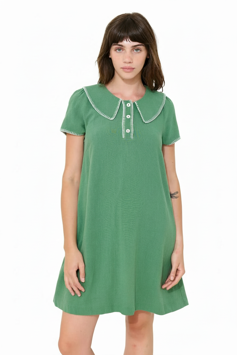 Woman in a green short-sleeve dress with a Peter Pan collar and white stitching.