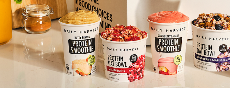 Daily Harvest protein smoothies and oat bowls in banana and berry flavors, displayed on a kitchen counter.