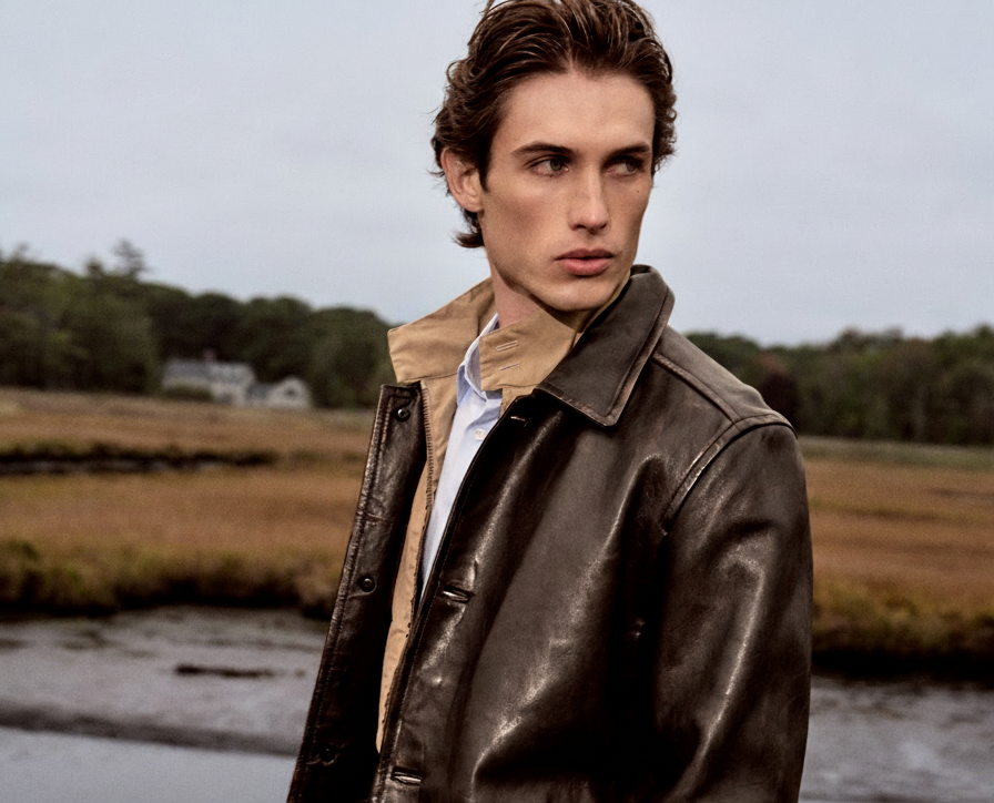 an image of a man in a leather jacket standing in front of a river