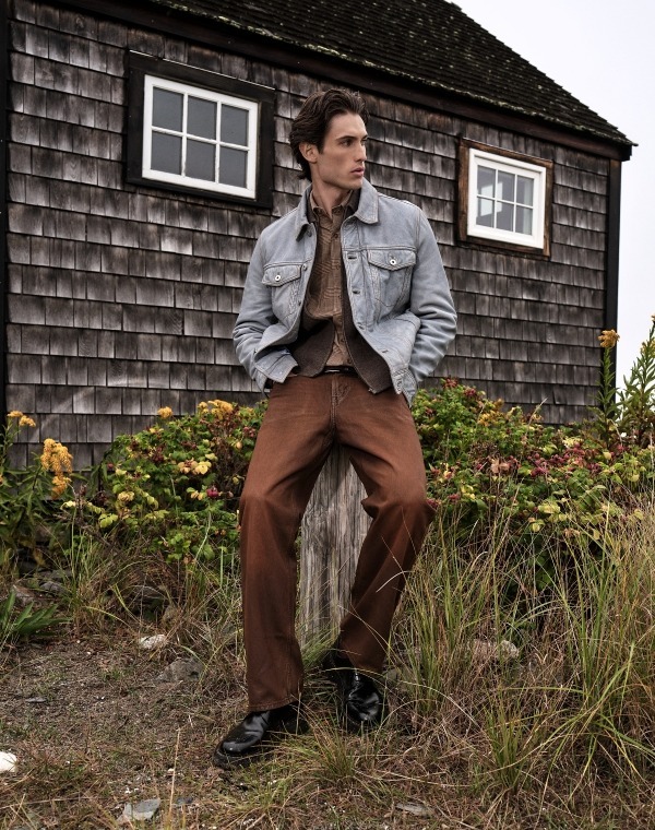 an image of a man in a suit and tie leaning against a wooden fence