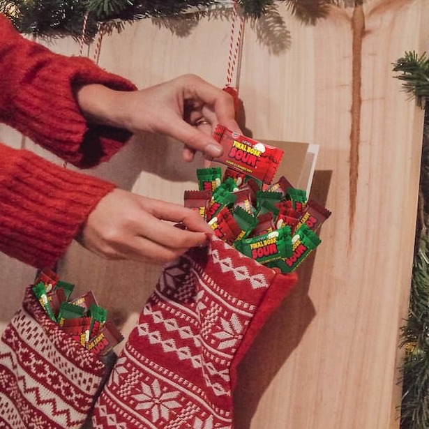 A child picks a Final Boss Sour fun-sized watermelon kiwi from a holiday stocking