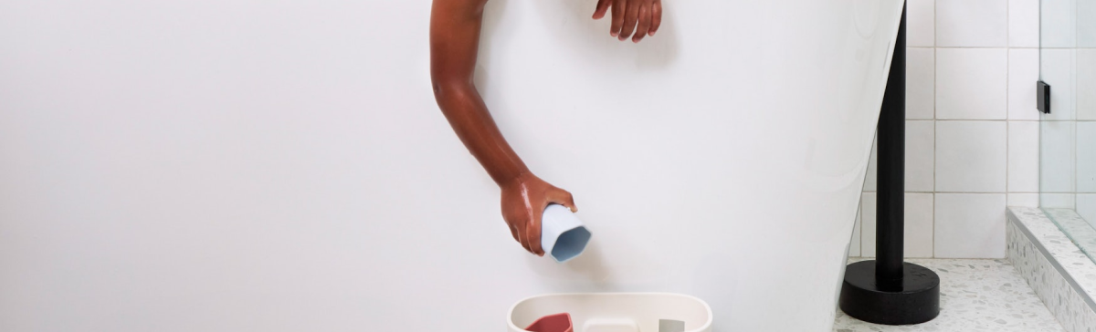 Baby reaching down in bath putting toys away