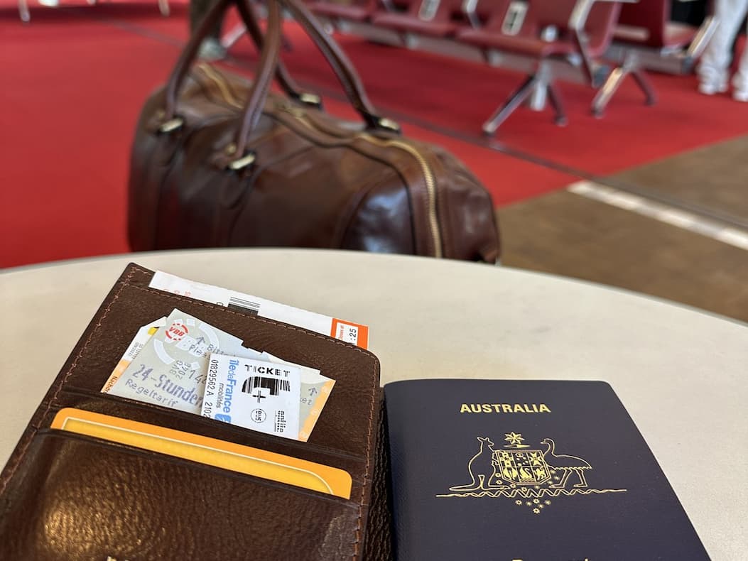 The passport cover, boarding pass tucked in, the duffle at the gate behind.