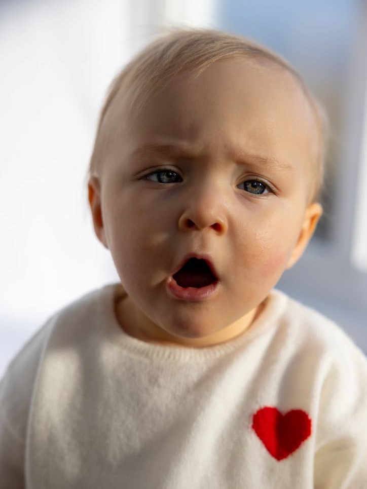 Baby in weißem Kaschmirpullover mit Herz