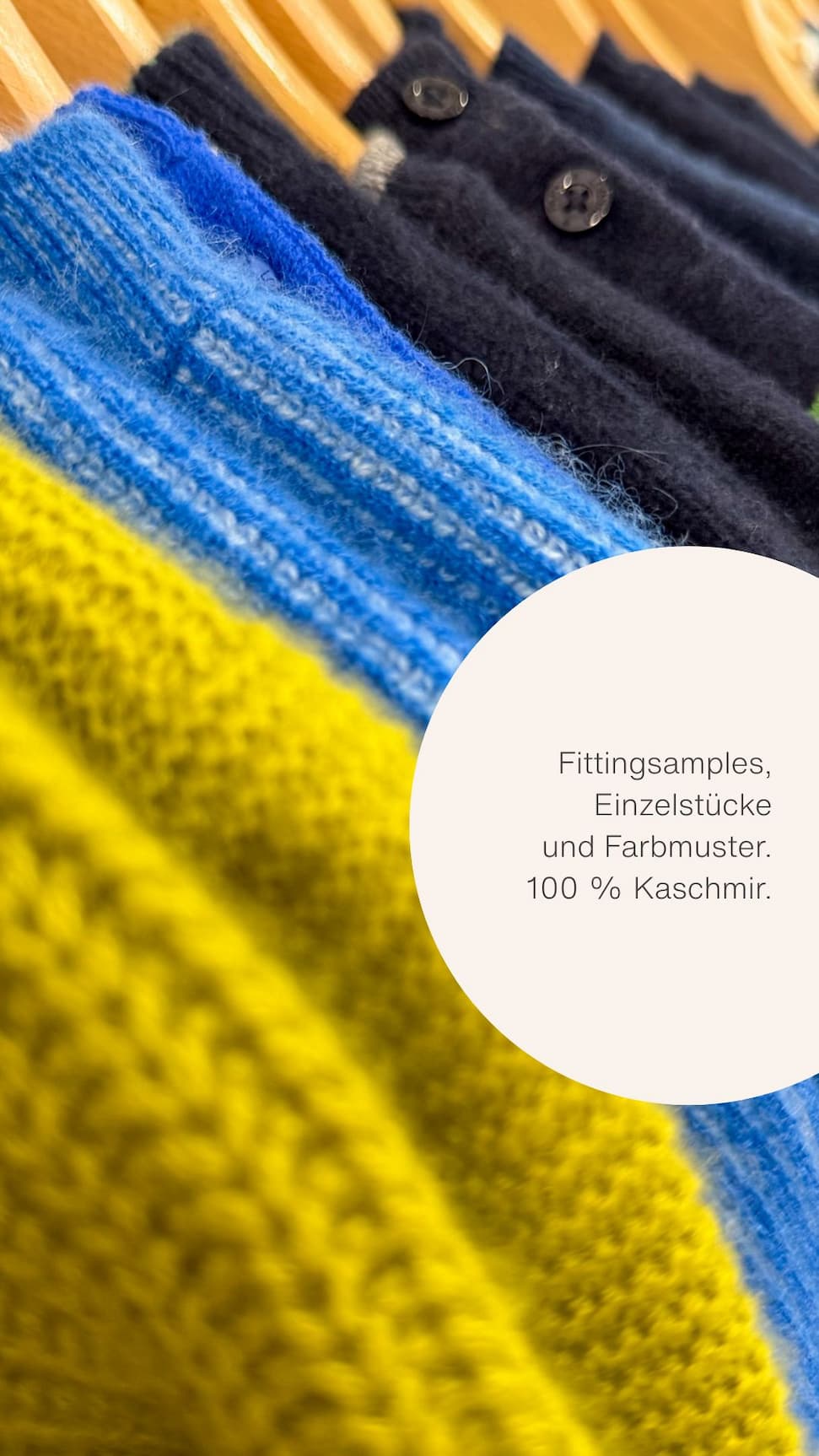 Ständer mit Kaschmirteilen auf Bügeln in bunten Farbtönen Ständer mit Kaschmirteilen auf Bügeln in bunten Farbtönen