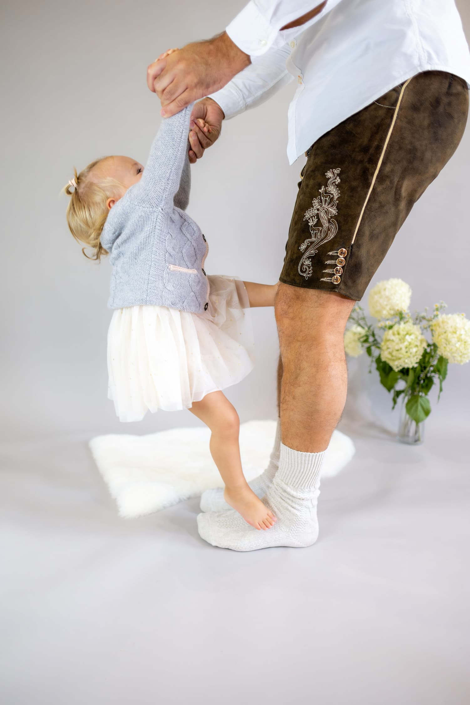 Toddler Mädchen in Kaschmirjacke MAXI hängt an den Händen des Papas und klettert an ihm hoch