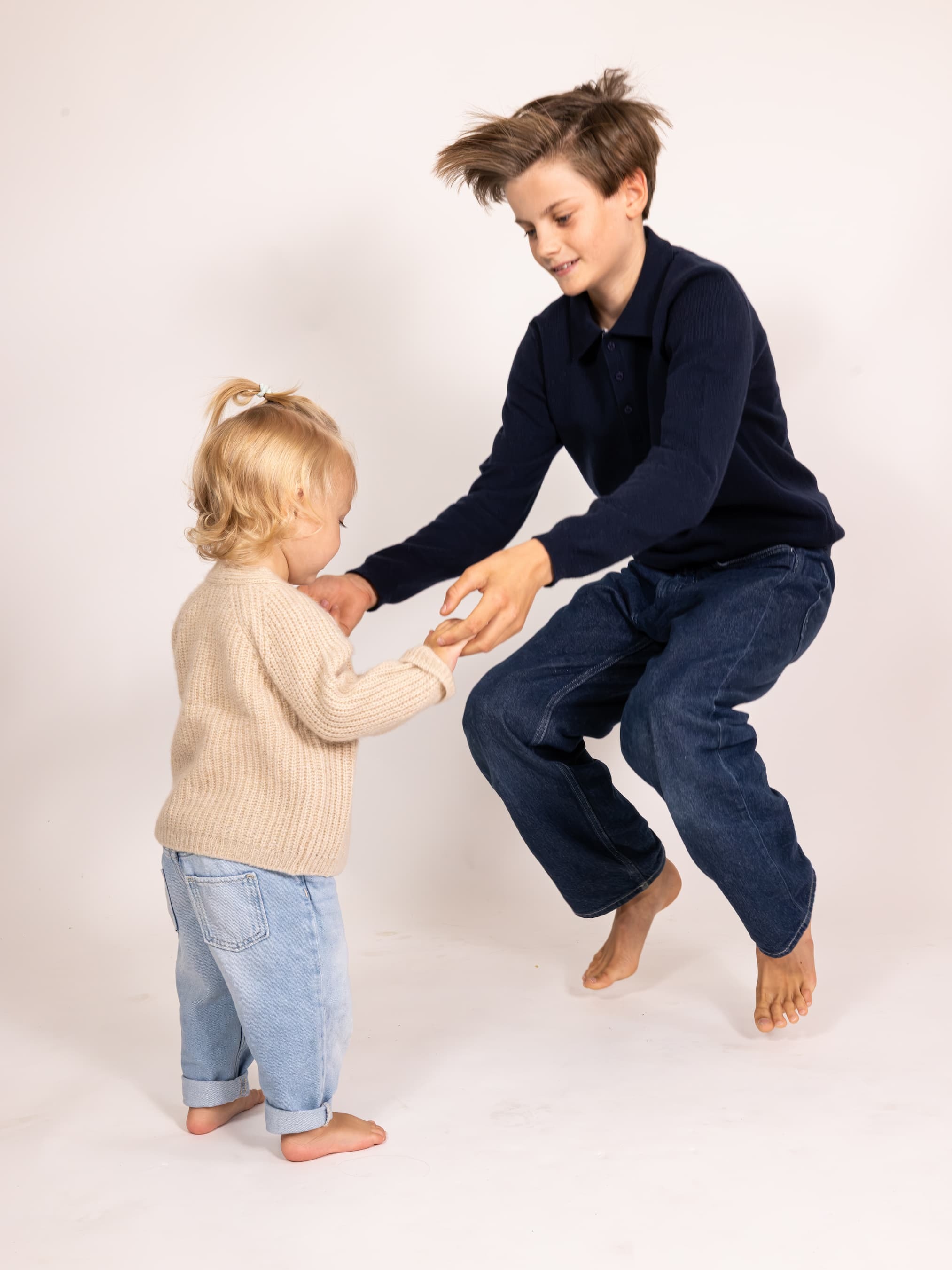 Springender Junge in Pullover NOAM mit Toddler-Girl an der Hand
