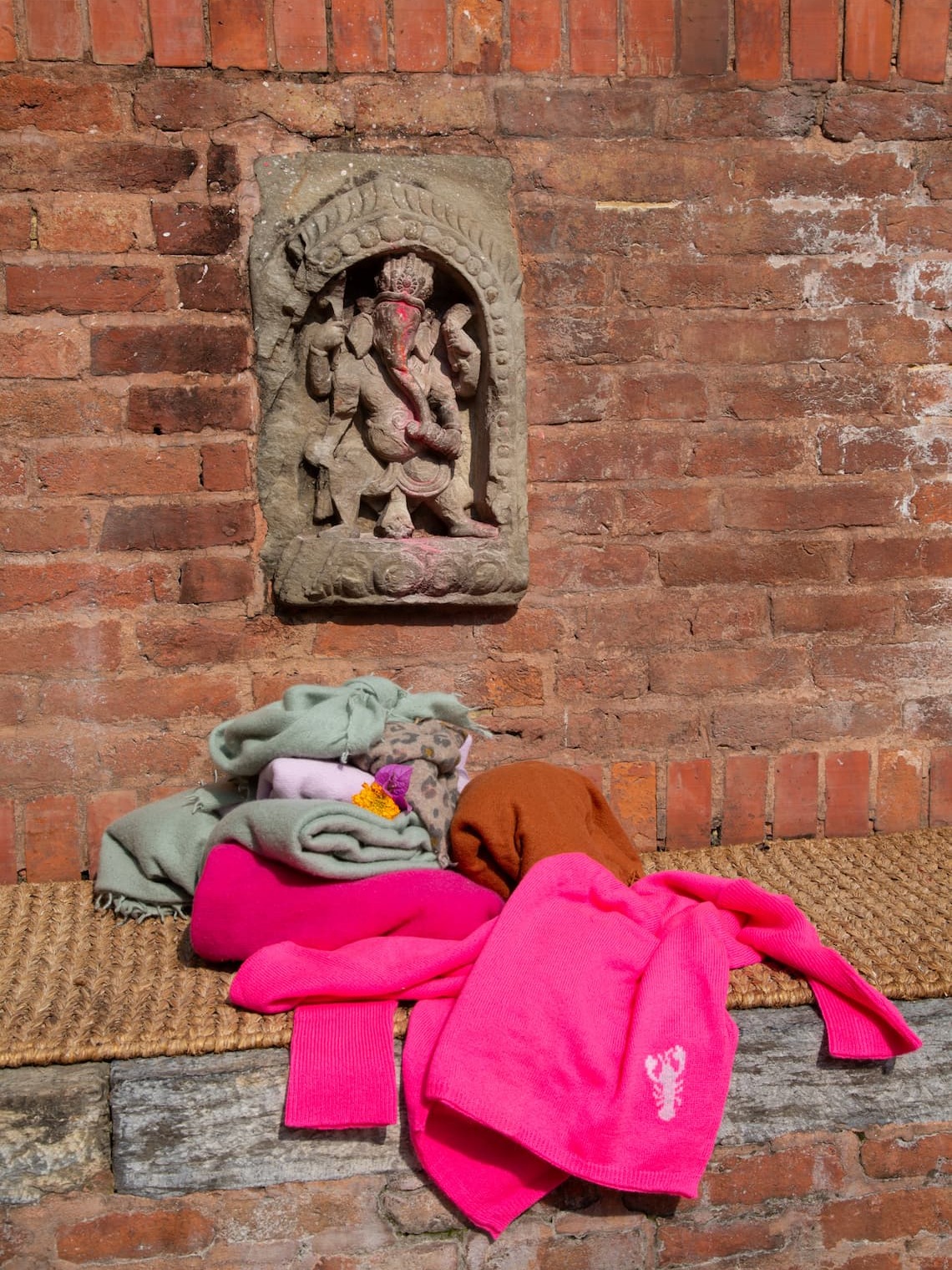 Stilleben Kaschmirteile in Neonpink vor Backsteinwand