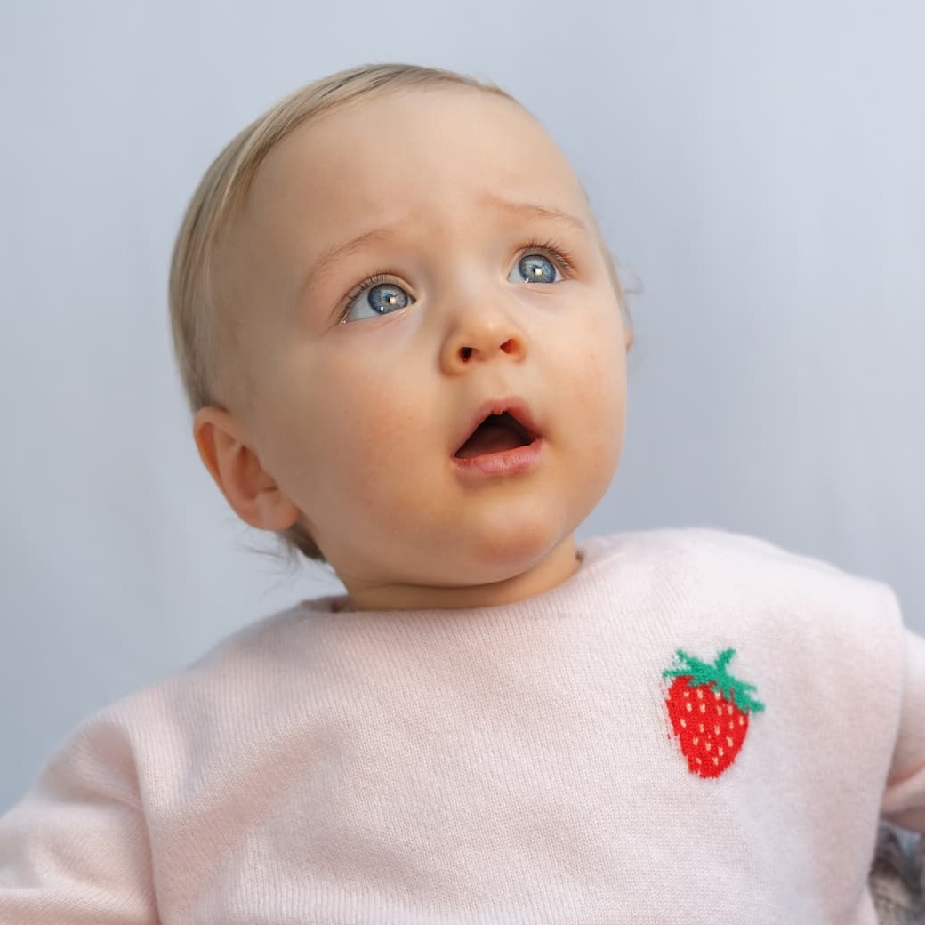 Baby in Pullover mit Erbeer-Intarsie