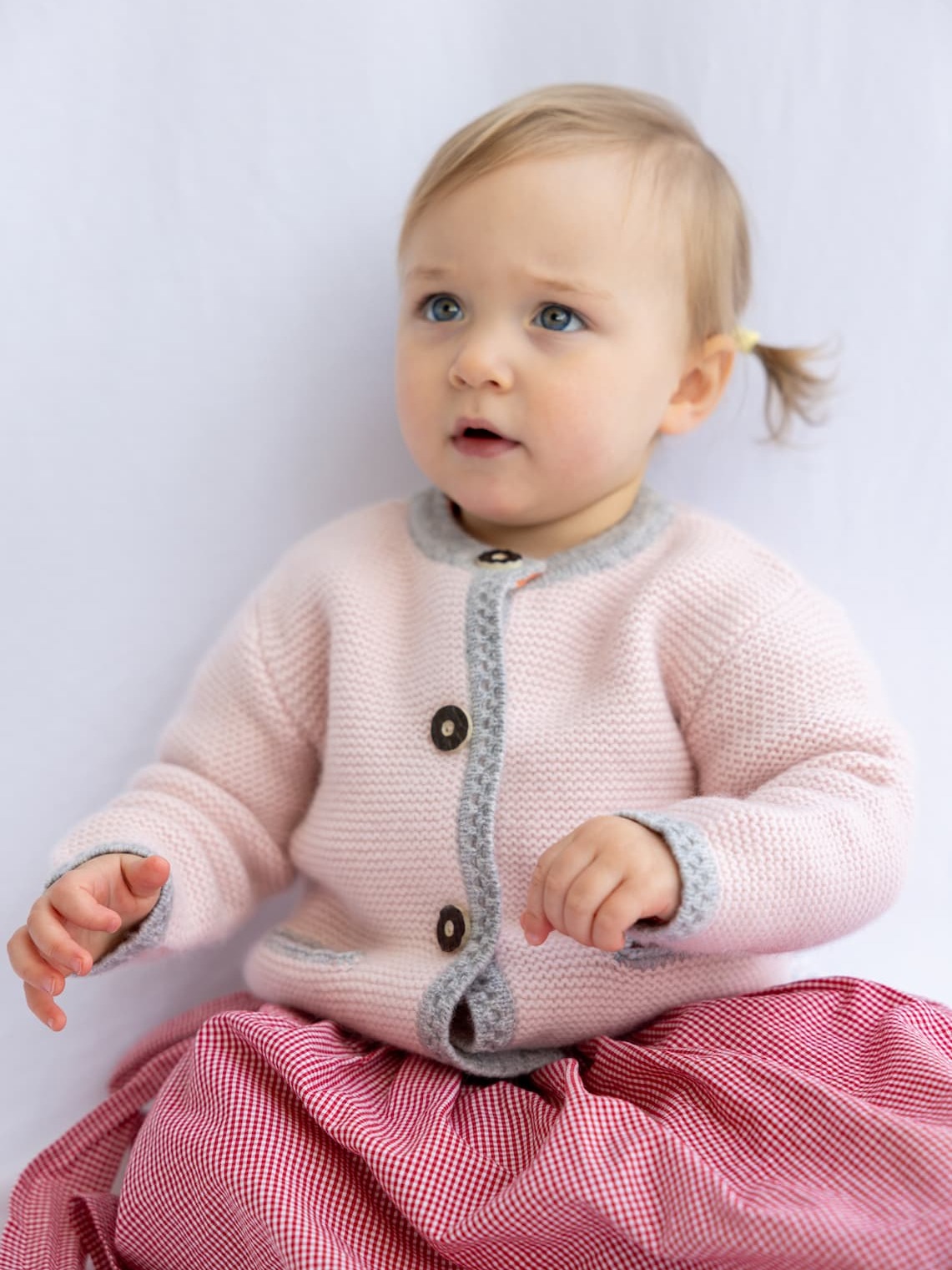 Sitzendes Babymädchen in Dirndl und mit Kaschmir-Trachten-Cardigan LENI