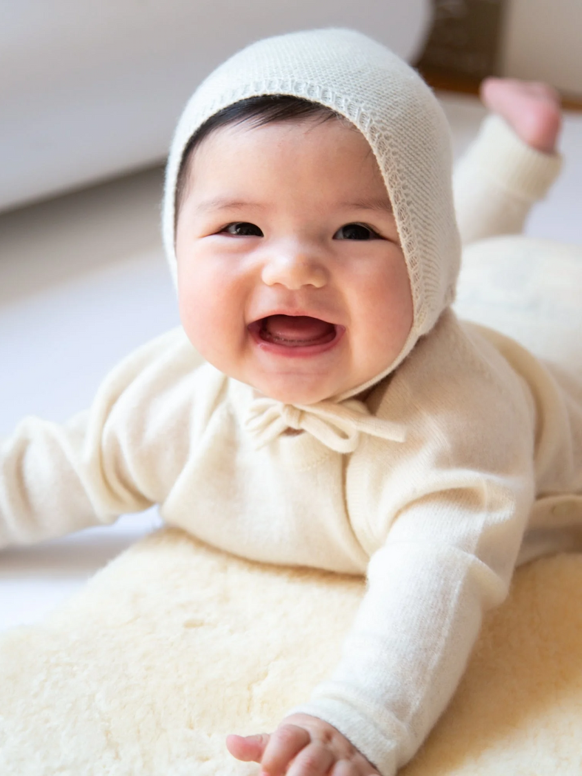 Lachendes Baby in Baby Set NIKA mit Baby-Haube JOJO mit Bindebändern