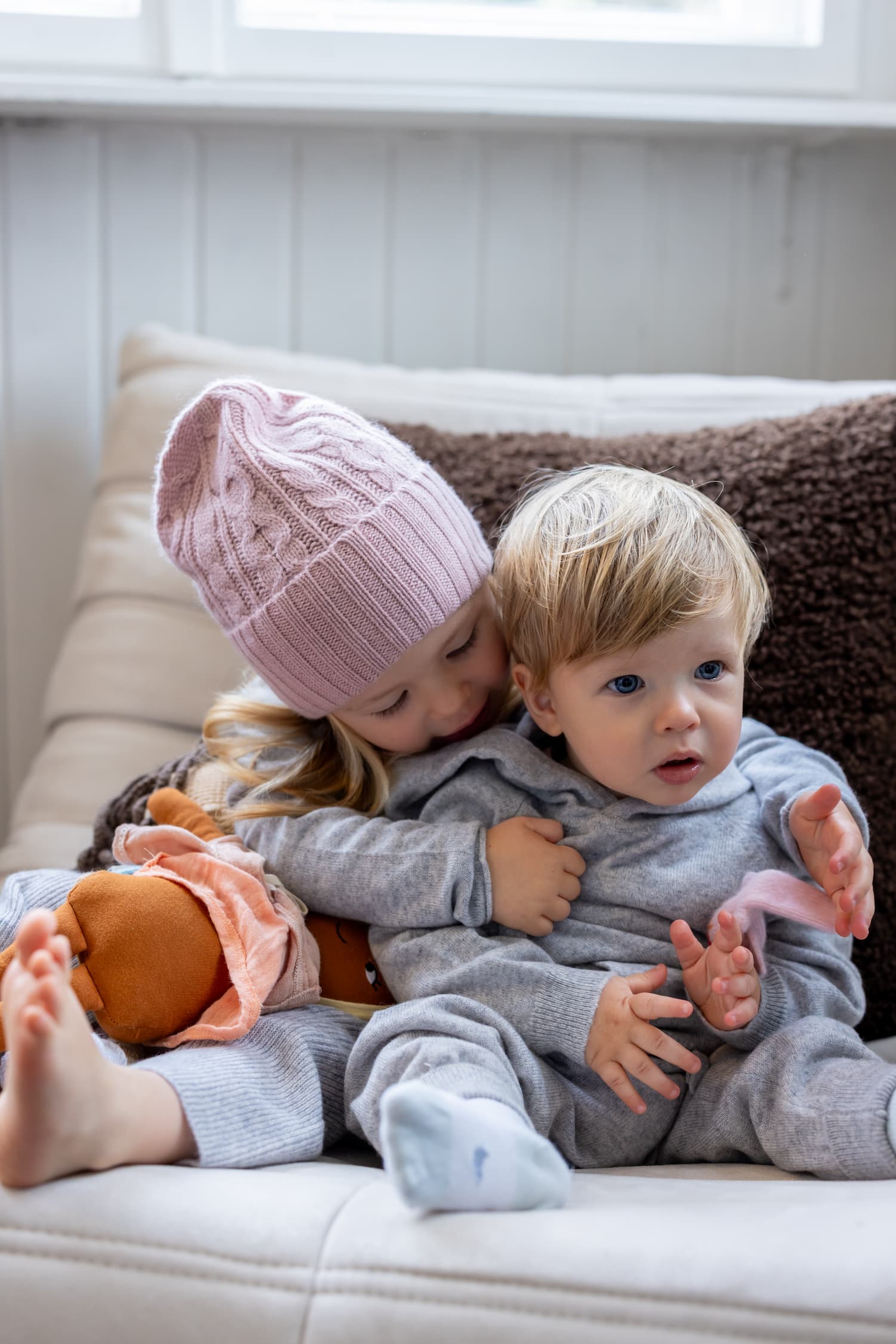 Geschwisterpaar in Kaschmiroutfit auf Sofa