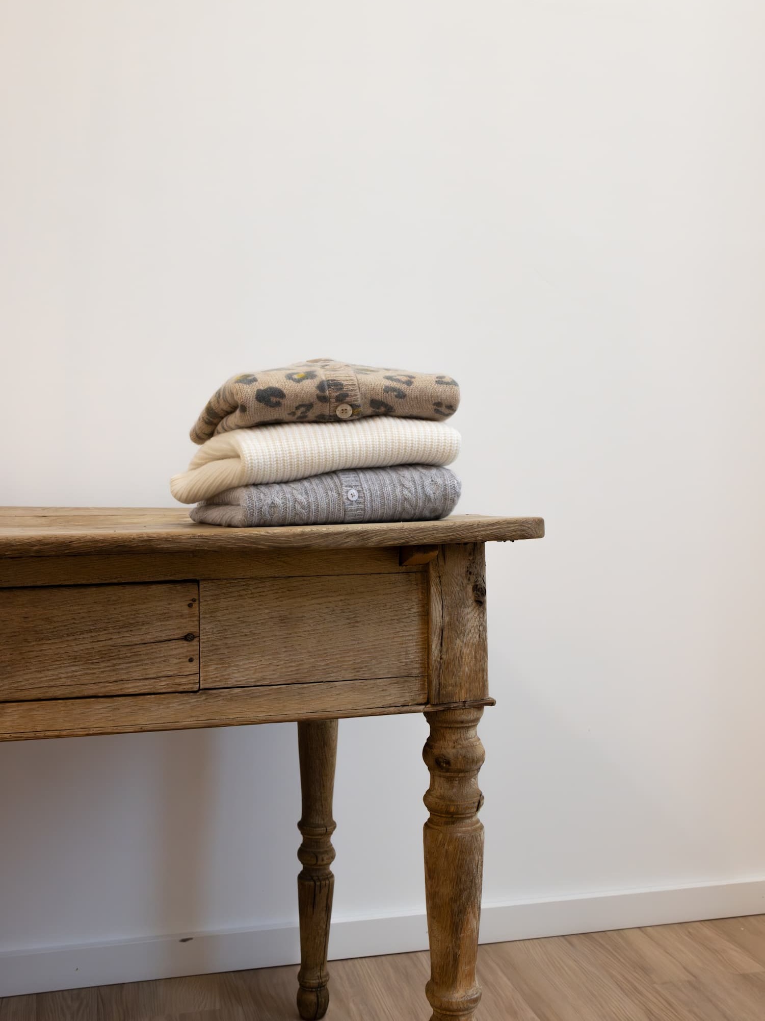 Stapel Kaschmir-Oberteile auf Holztisch