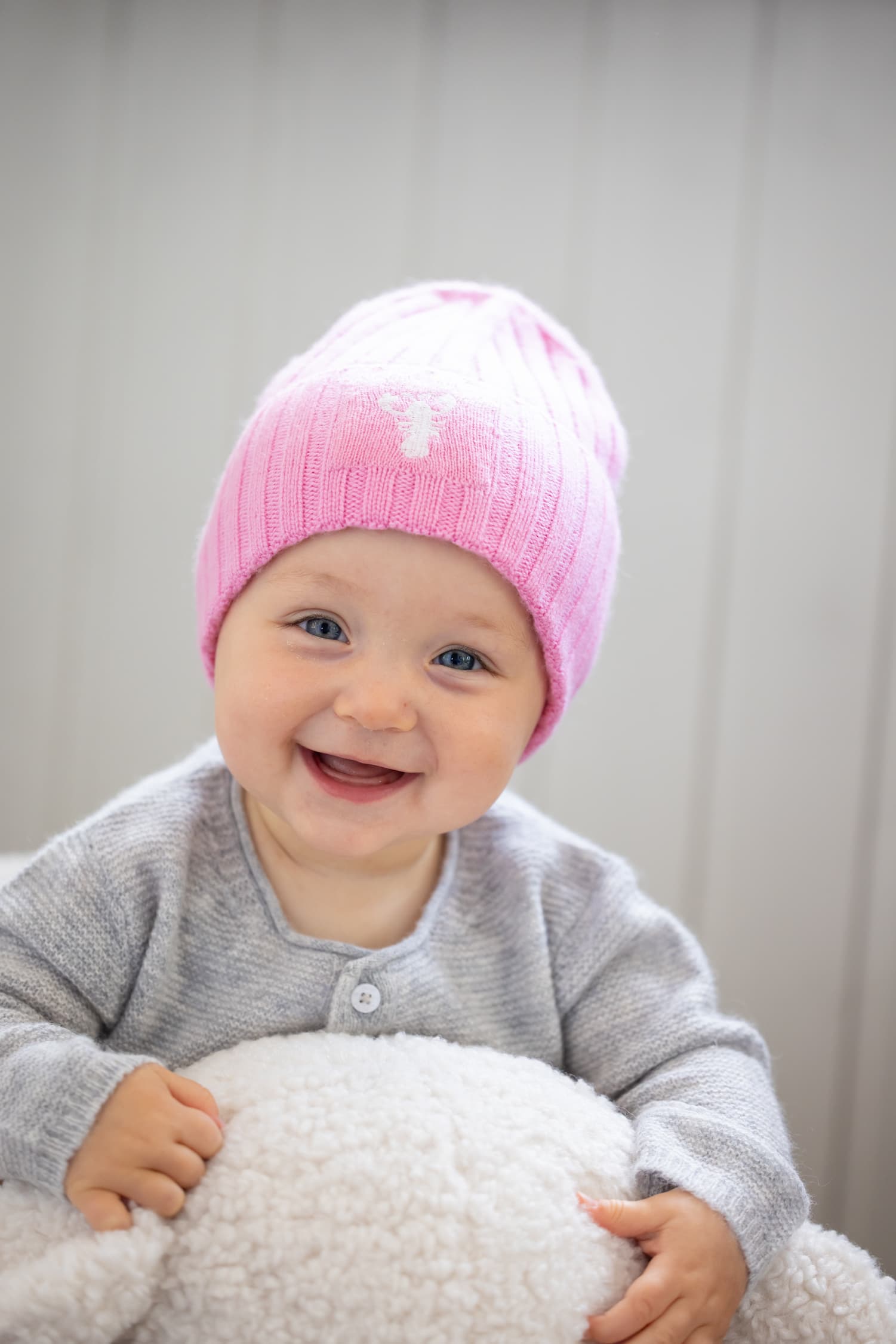 Porträt lächelndes Baby sitzend mit Mütze MATTI in Rosa