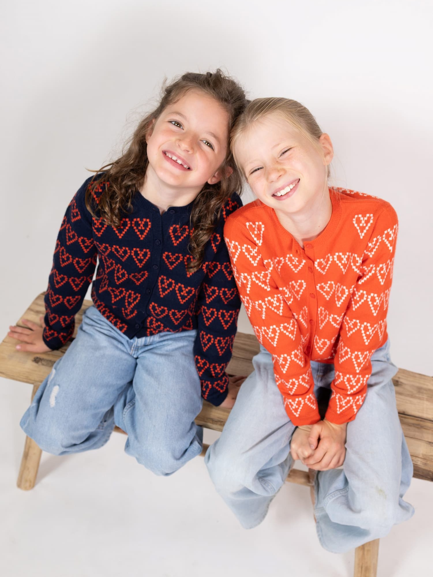Zwei nach oben schauende lächelnde Mädchen in Strickjacke LITTLE HEARTLINE