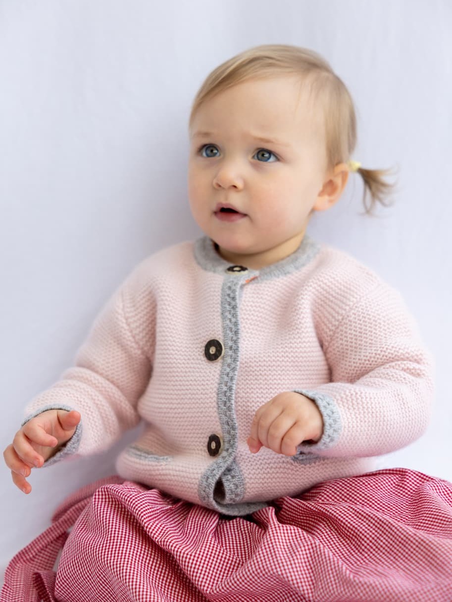 Sitzendes Mädchen in Trachten-Cardigan