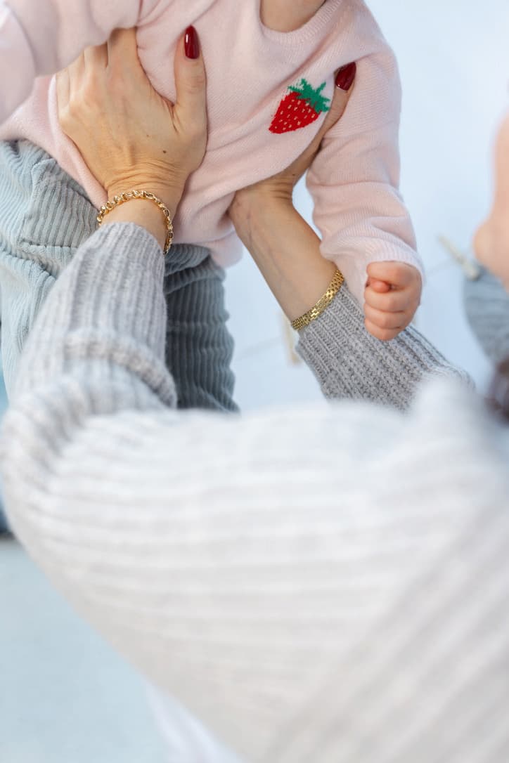 Ausschnitt Baby in Pullover mit Erdbeere wird hochgehoben