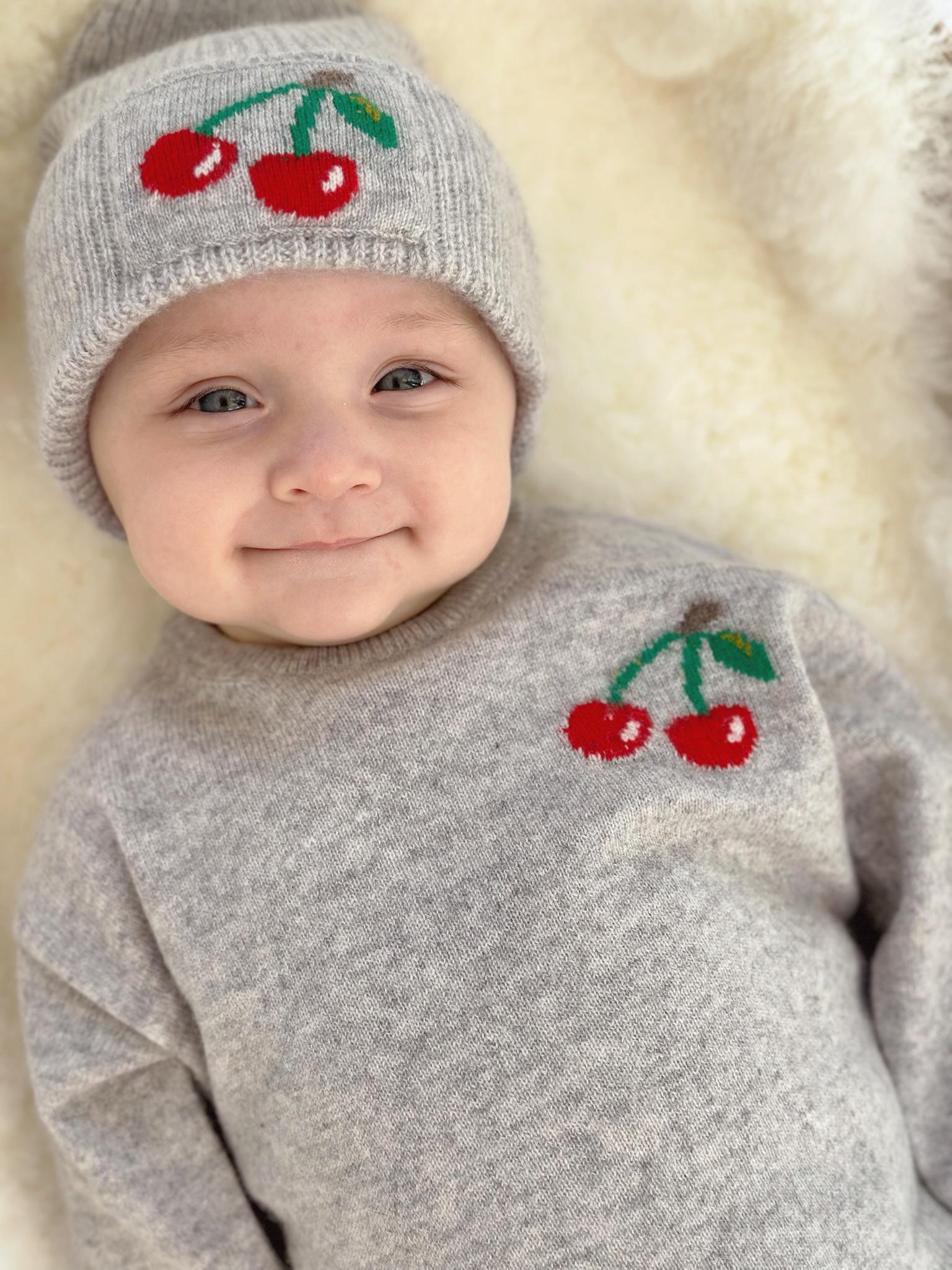 Baby in Pullover und Mütze mit Kirsch-Intarsie