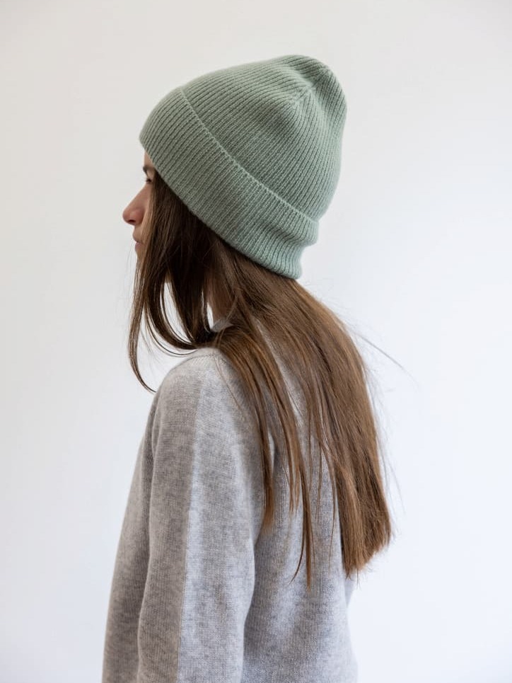 Mädchen seitlich mit salbeifarbener Kaschmirmütze und grauem Cardigan Mädchen seitlich mit salbeifarbener Kaschmirmütze und grauem Cardigan