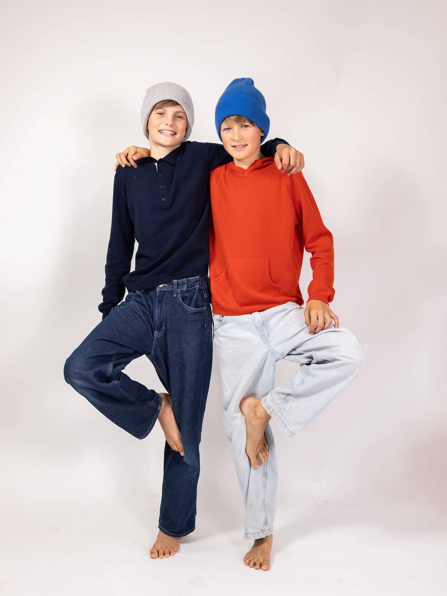Zwei Jungs in Yoga-Baumpose mit Hoodies und Kaschmir-Mützen