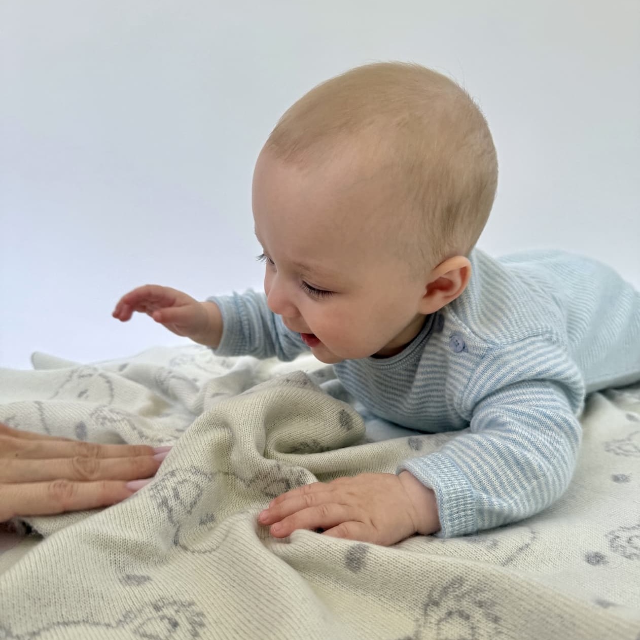 Baby im Overall MINISTRIPE liegend auf Babydecke