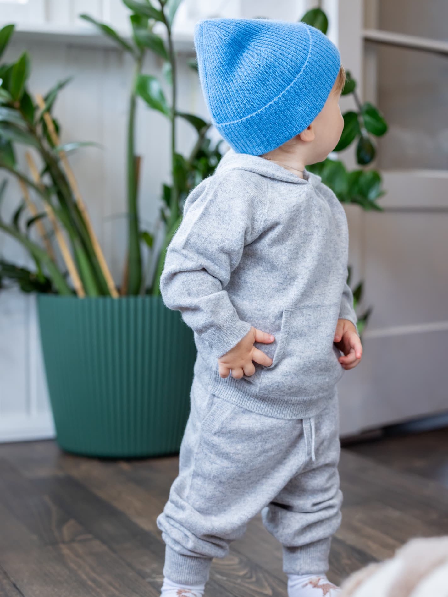kleiner Junge stehend im Kaschmir-Outfit Hellgrau mit Mütze in Ozeanblau