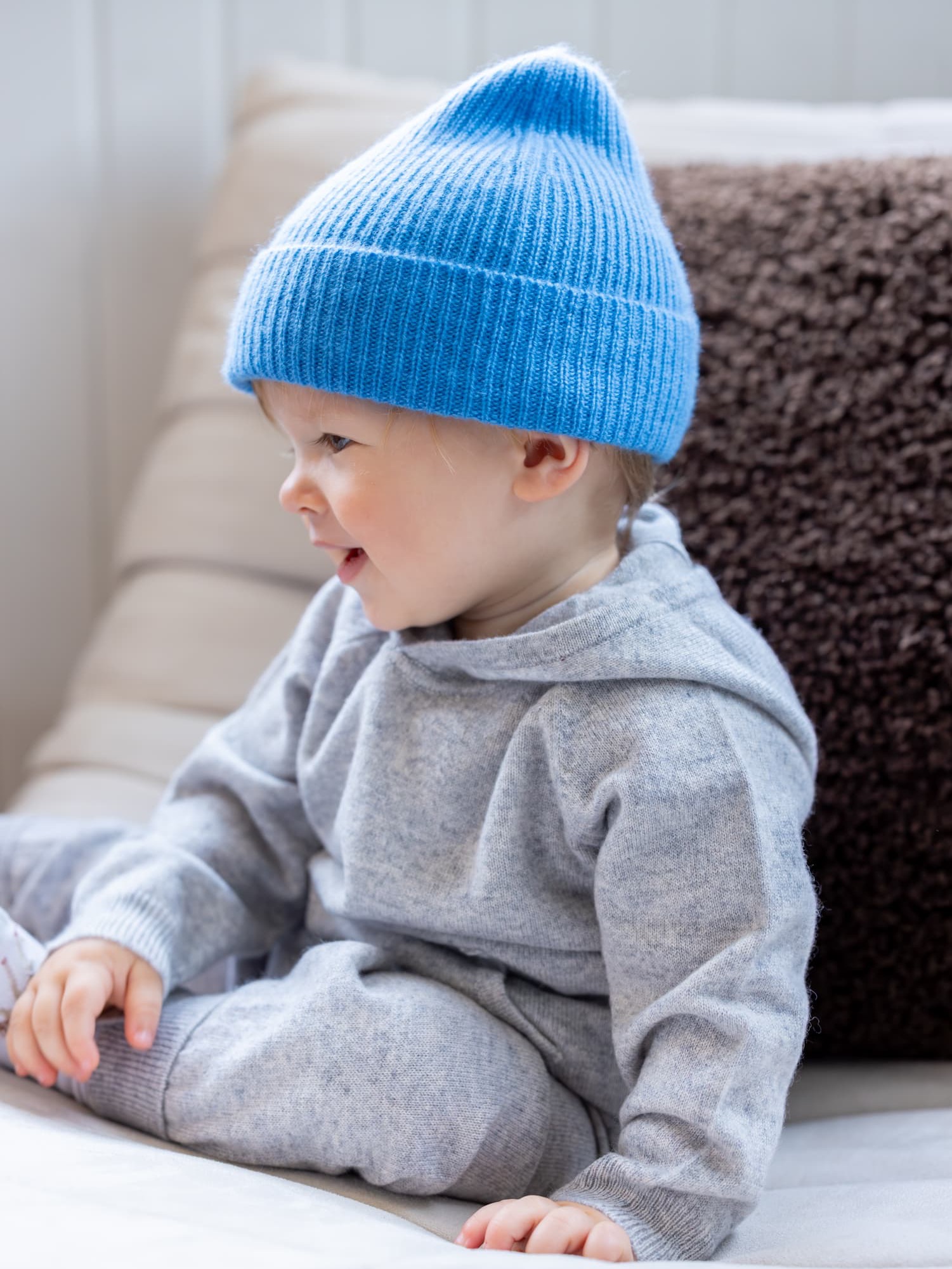 Kleiner Junge sitzend im Kaschmir-Outfit mit Mütze