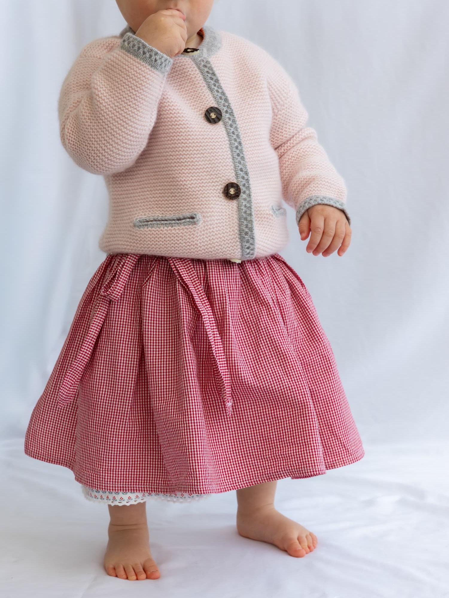 Stehendes Babymädchen mit Kaschmir-Trachtenjacke und Dirndlrock