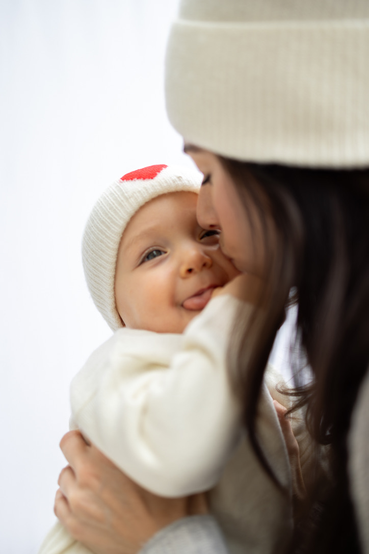 Auschnitt Mutter küsst Baby mit Kaschmirmütze