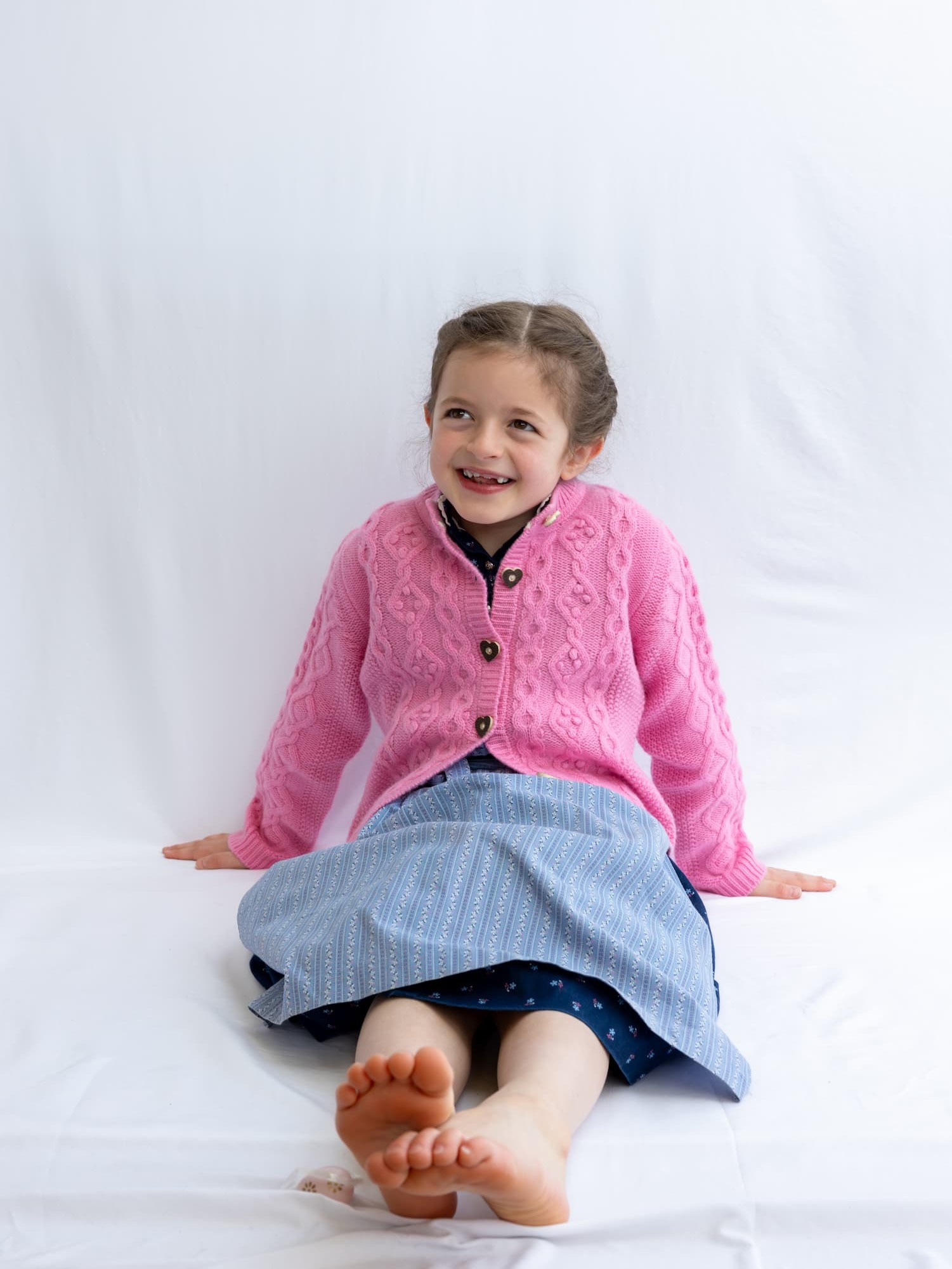 Sitzendes Mädchen in Dirndl und mit Kaschmir-Trachten-Cardigan Charlotte