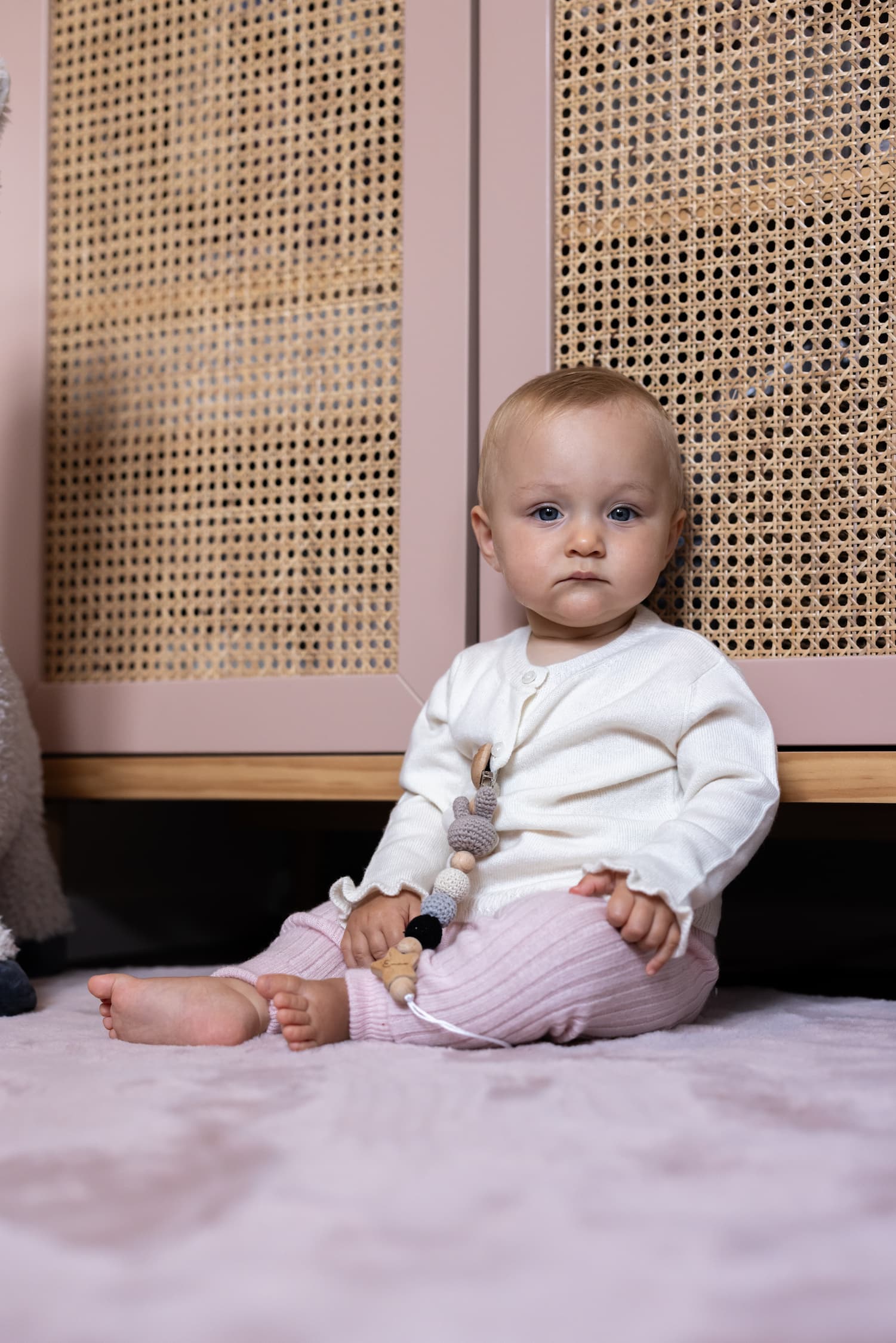 Baby sitzend mit weisser Strickjacke SANNA