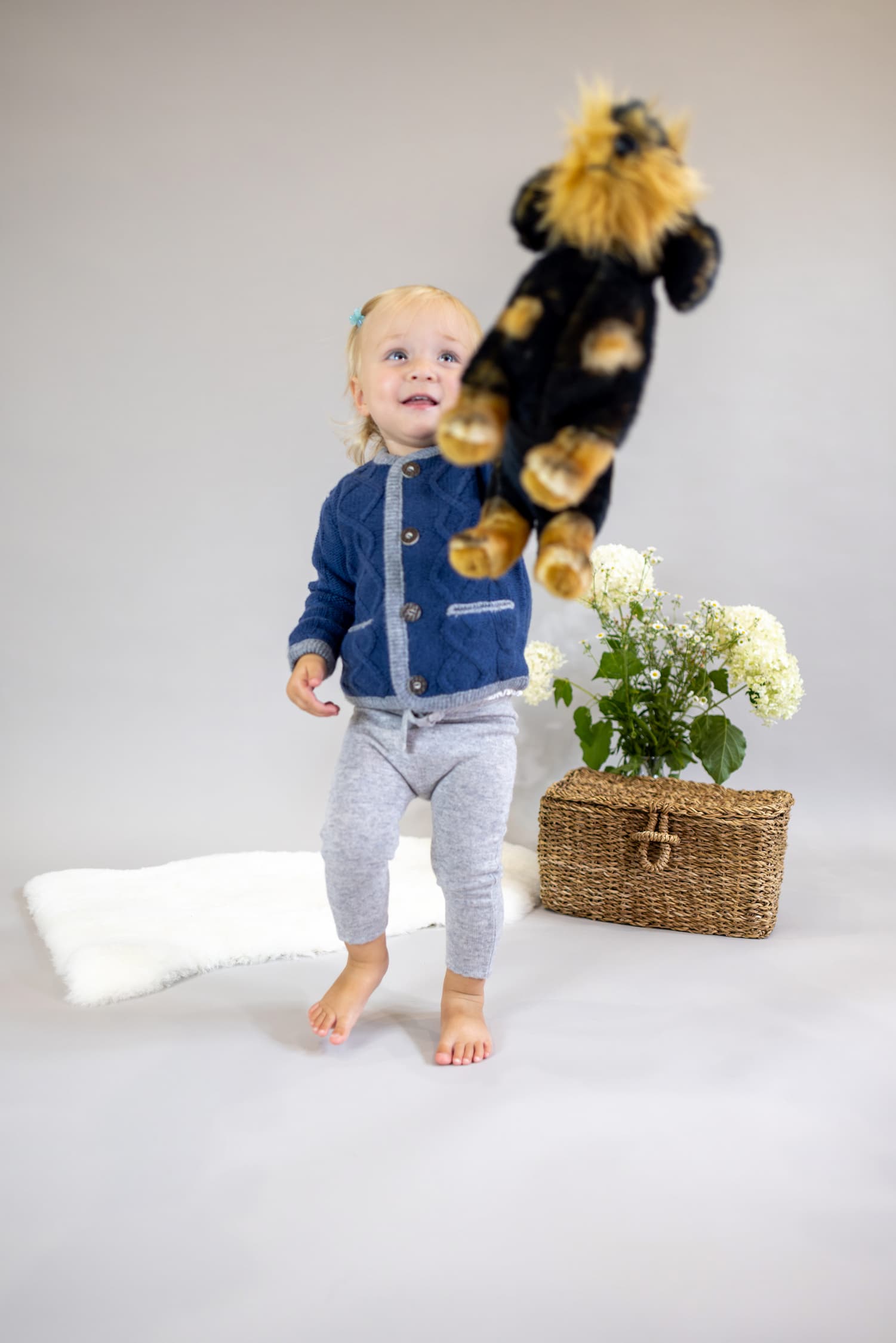 Toddler Mädchen in Kaschmirjacke MAXI streckt uns ihr Kuscheltier entgegen.