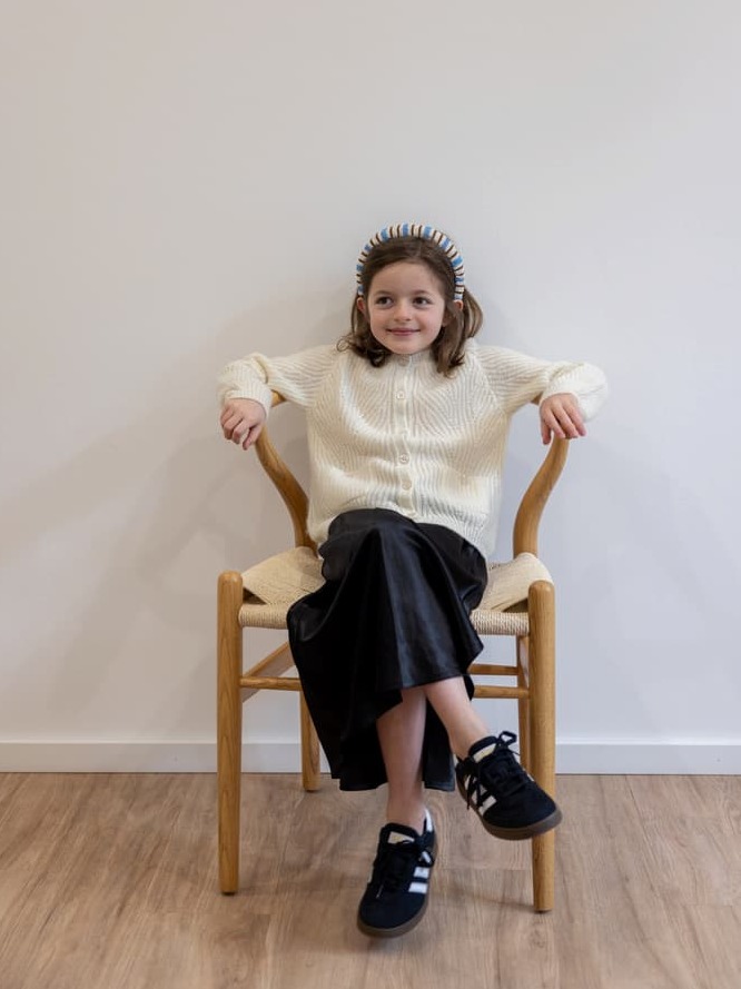 Sitzendes Mädchen mit Kaschmir-Cardigan JULIANNE