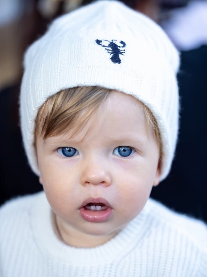 Porträt Junge mit weisser Kaschmirmütze mit Lobster-Emblem