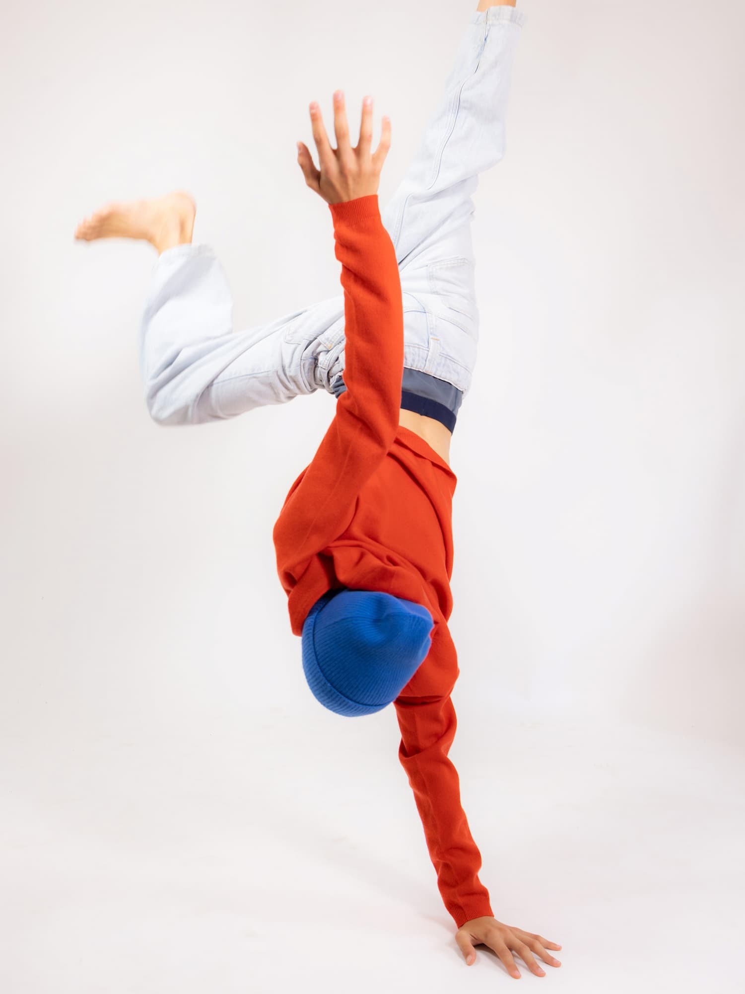 Junge macht Handstand auf einer Hand mit Hoody JONA in Korallenrot.
