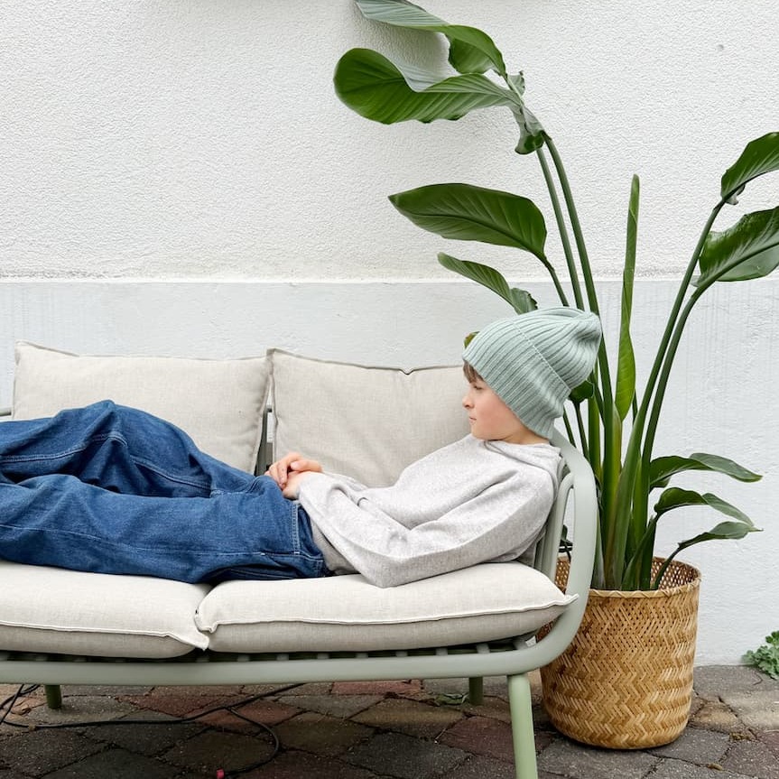 Junge auf Sofa liegend mit Beanie-Mütze MATTI in Salbei