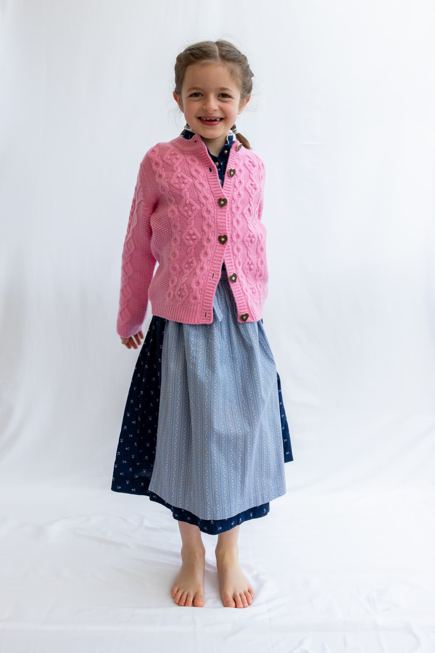 Stehendes Mädchen in Trachten-Cardigan und Dirndl