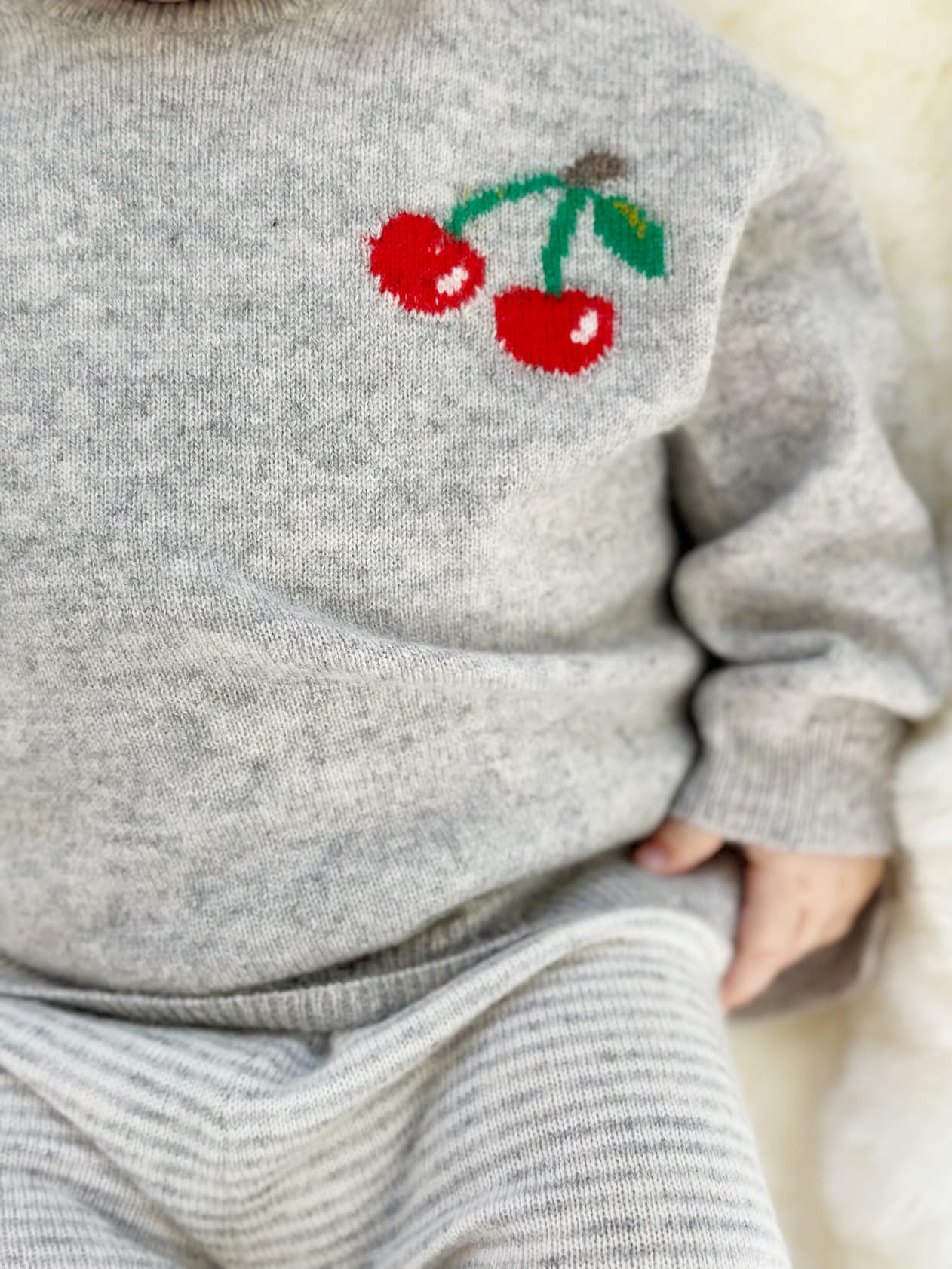 Detail Baby in Pullover mit Kirsch-Intarsie