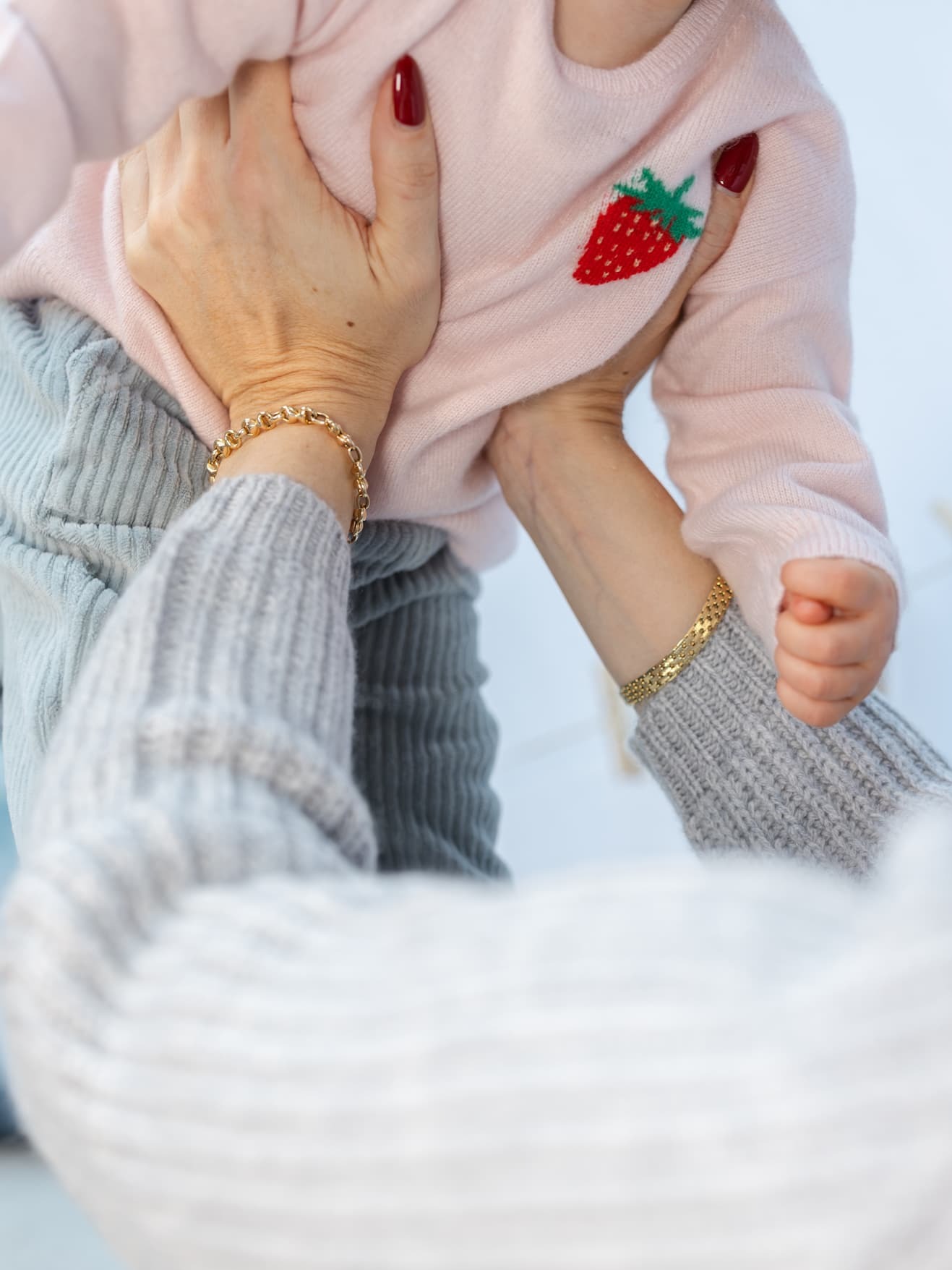 Detail Baby in Pullover mit Erbeer-Intarsie