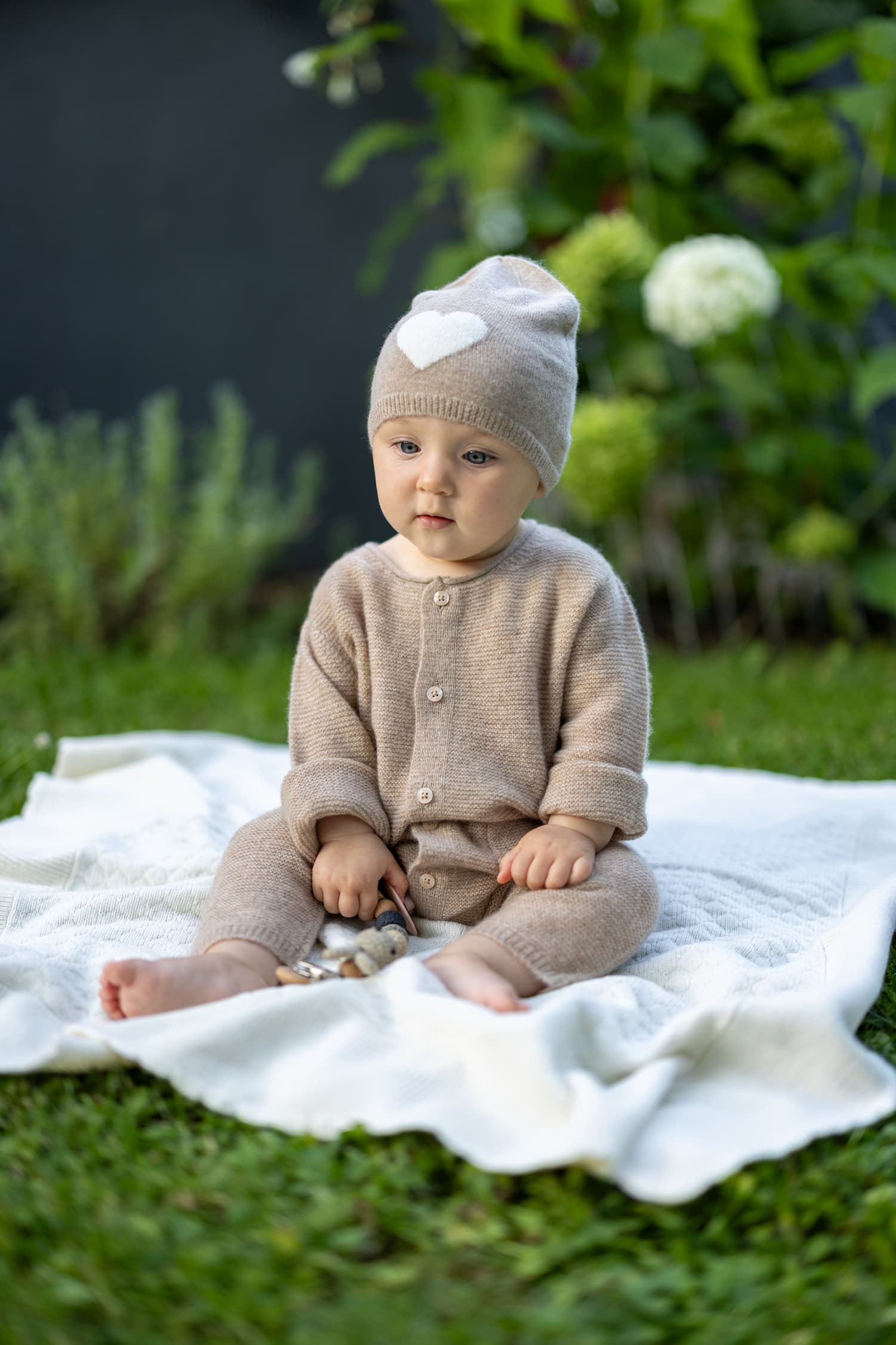 Baby sitzend in Kaschmir Overall ANOUK mit Mütze HEART in Beige