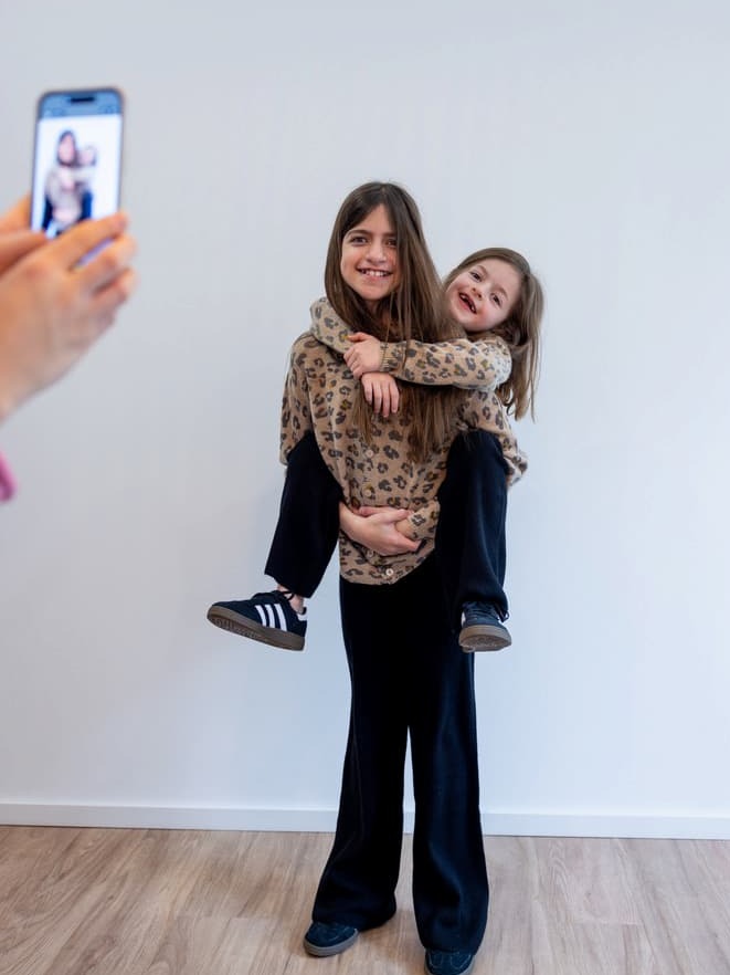 Zwei Mädchen Huckepack mit Kaschmir-Cardigan LEO und Hose MARLENE