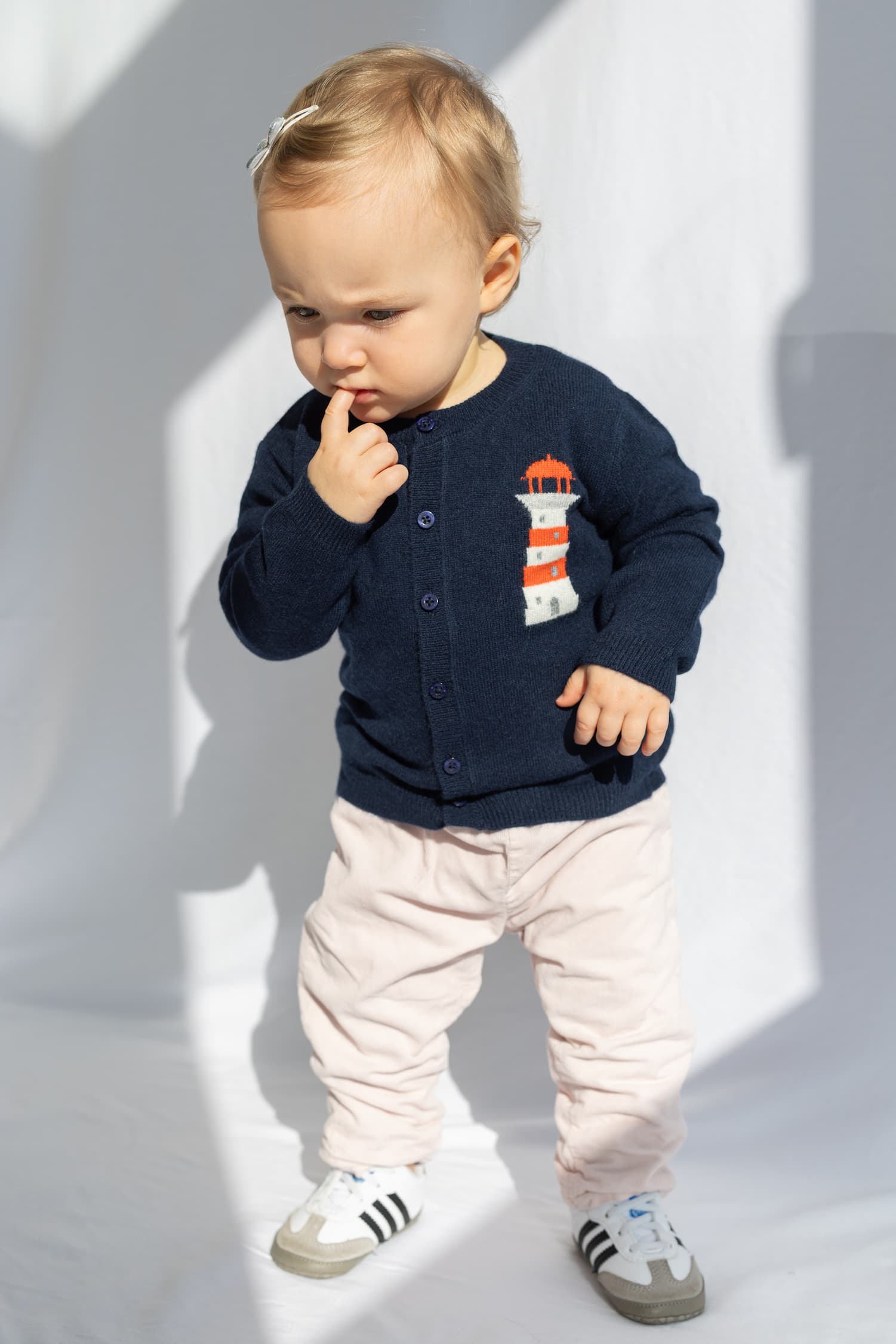 Babymädchen stehend mit Strickjacke mit Leuchtturm-Intarsie
