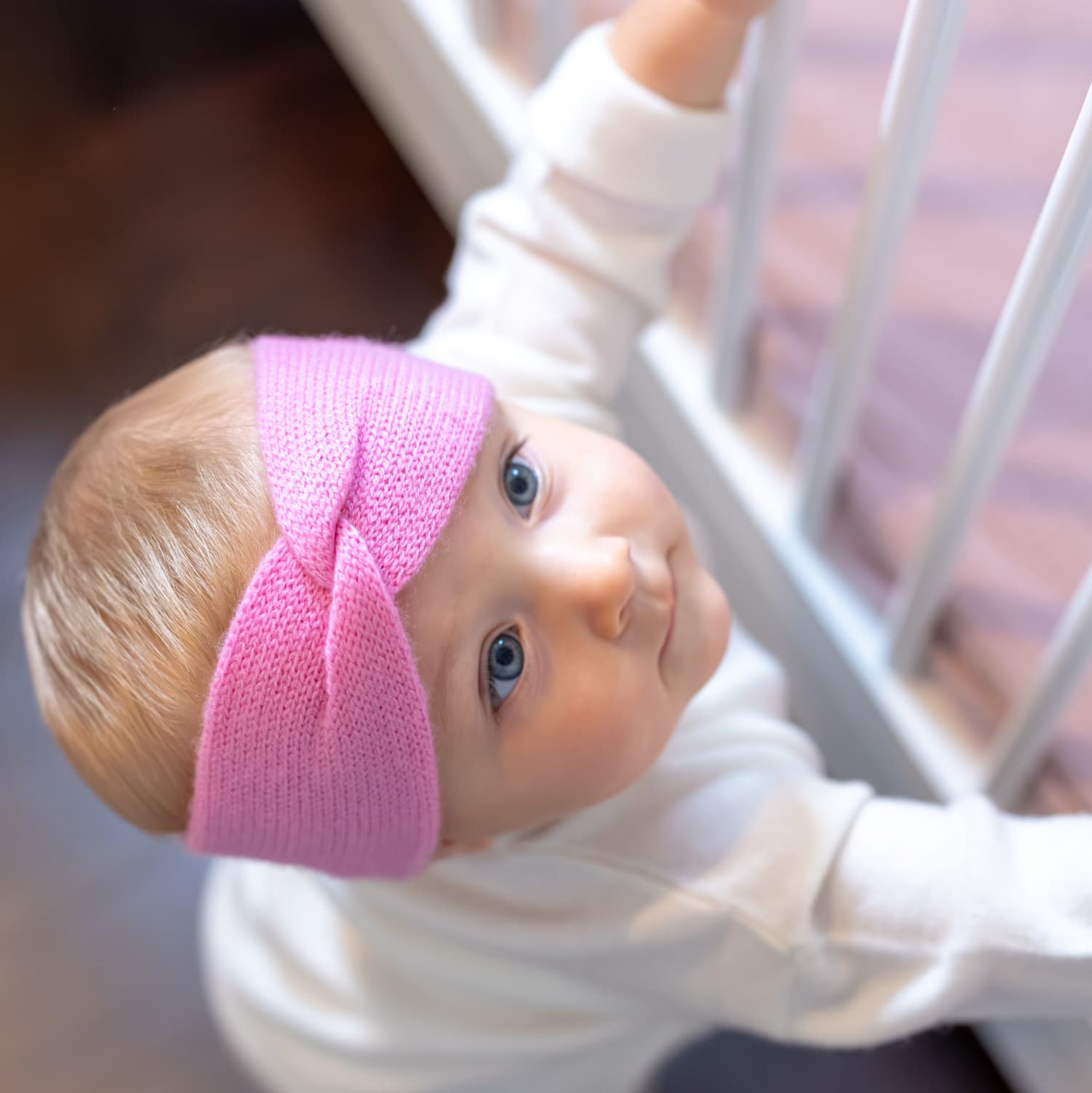 Baby blickt hoch mit Stirnband MAXI in Rosa