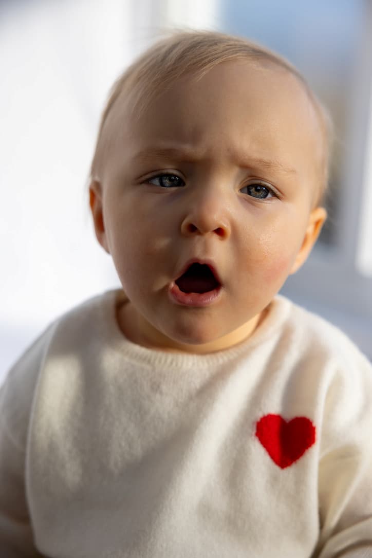 Baby gähnend mit Herz-Pullover