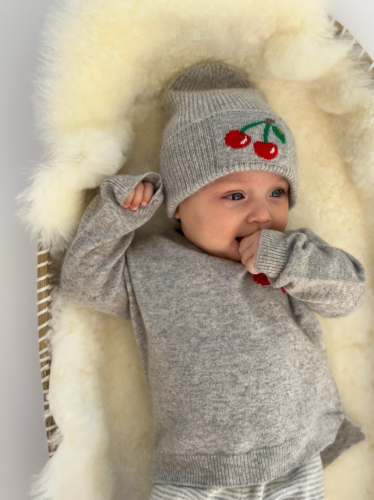 Baby in Pullover und Mütze mit Kirsch-Intarsie