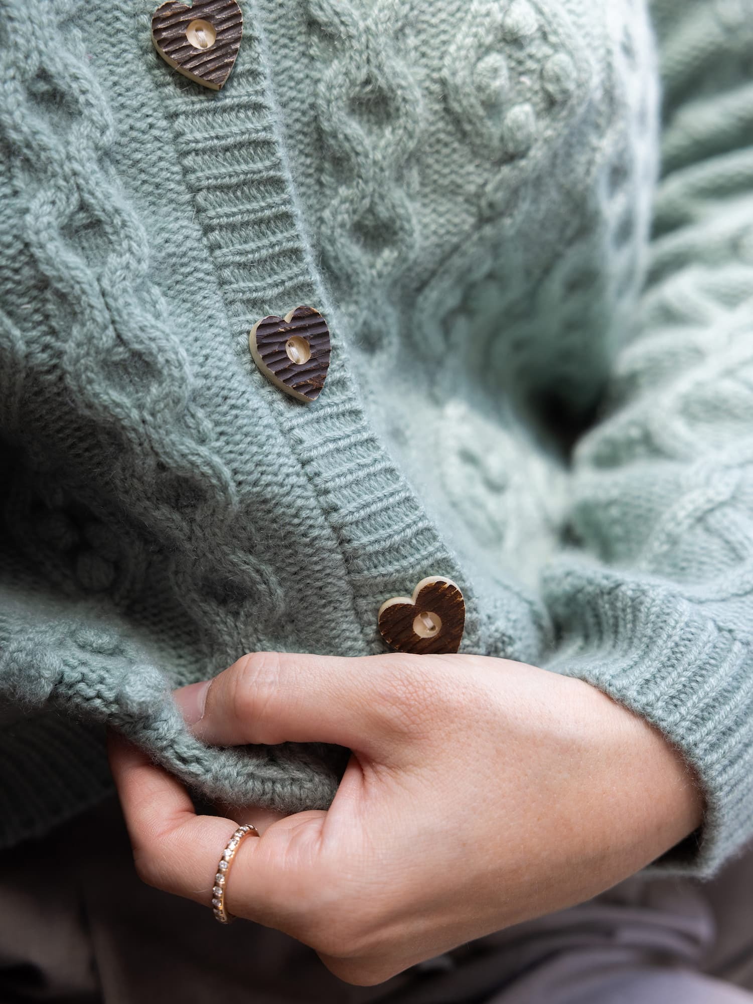 Detail Ausschnitt Cardigan CHARLOTTE in Salbei mit Frauenhand