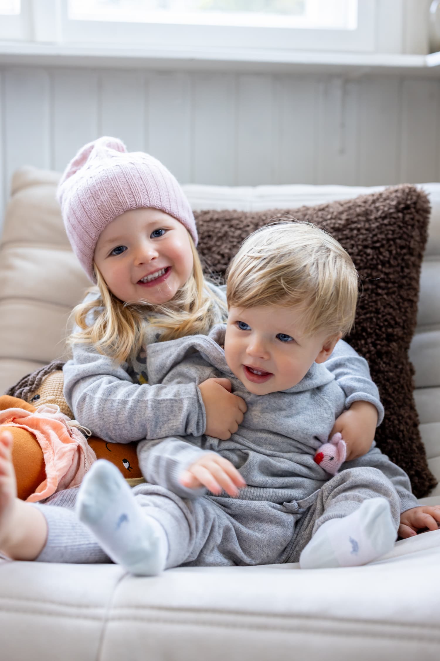 Geschwisterpaar auf Sofa sitzend in Kaschmir-Outfit