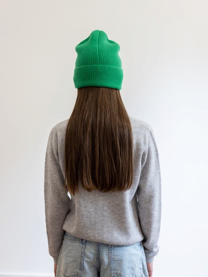 Mädchen von hinten mit grüner Kaschmirmütze und grauem Cardigan