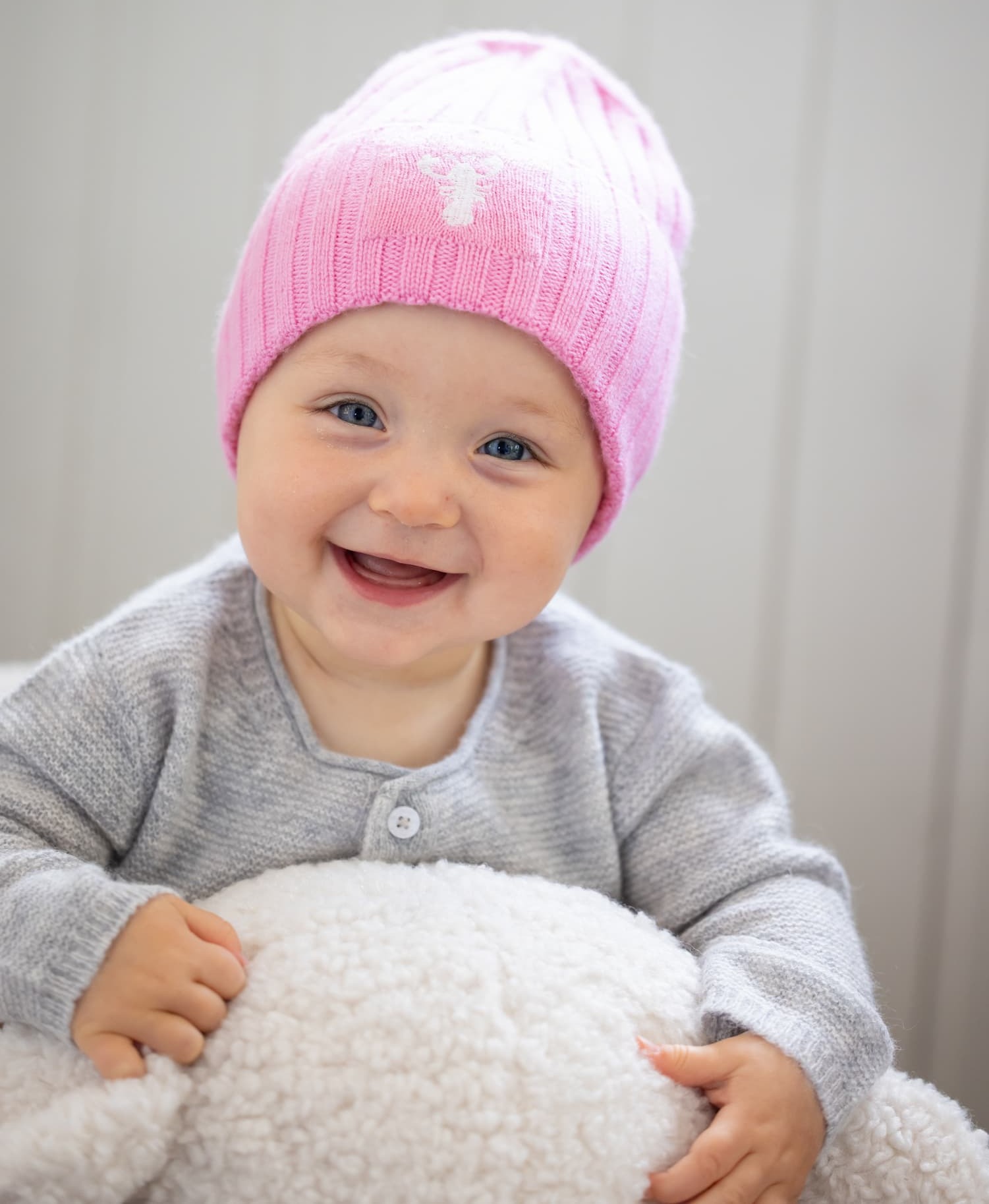 Baby strahlend lächelnd mit Mütze MATTI in Rosa